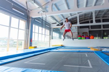 Fitness, eğlence, eğlence ve spor aktivite konsepti - Yakışıklı mutlu adam kapalı bir trambolin üzerinde atlama