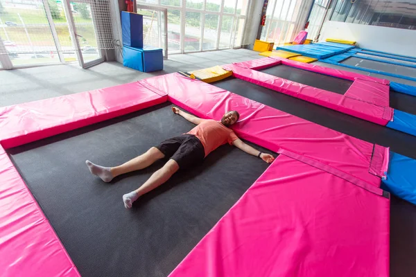 Fitness, diversão, lazer e esporte conceito de atividade - Homem deitado em um trampolim dentro de casa, vista superior — Fotografia de Stock