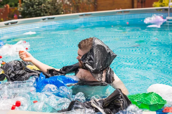 生態系、プラスチックごみ、環境緊急事態と水質汚染-ショックを受けた男は汚れたスイミングプールで泳ぐ — ストック写真