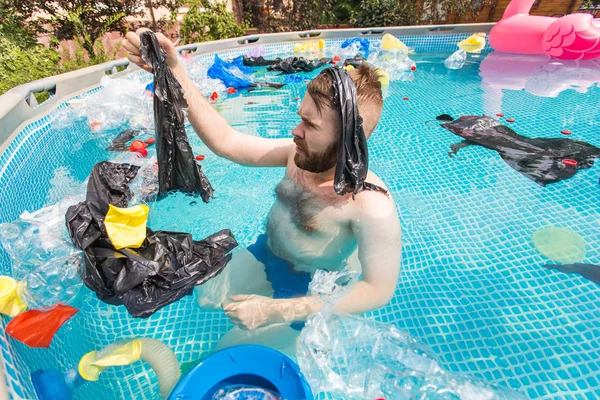 生態系、プラスチックごみ、環境緊急事態と水質汚染-ショックを受けた男は汚れたスイミングプールで泳ぐ — ストック写真