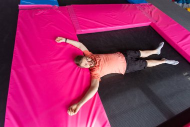 Fitness, eğlence, eğlence ve spor aktivitesi konsepti. Trambolinde uzanan adam, üst manzara.