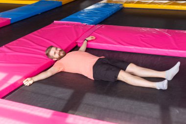 Fitness, eğlence, eğlence ve spor aktivitesi konsepti. Trambolinde uzanan adam, üst manzara.