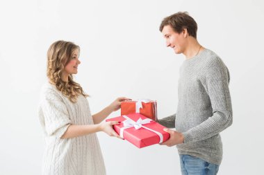Sevgililer günü, tatil ve hediye konsepti. Sevgililer Günü hediyesi olan mutlu genç çift beyaz bir arka planda izole edilmiş. Mutlu Adam kız arkadaşına hediye veriyor..