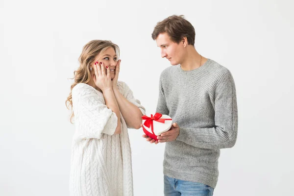 Giorno di San Valentino, vacanza e idea regalo. Felice giovane coppia con San Valentino presente isolato su uno sfondo bianco. Uomo felice che fa un regalo alla sua ragazza . — Foto Stock