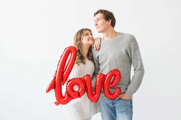 Dia dos namorados, férias e conceito de presente. feliz jovem caucasiano casal segurando amor palavra em forma de balão vermelho no fundo branco — Fotografia de Stock