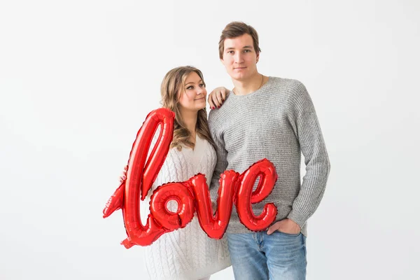 Dia dos namorados, férias e conceito de presente. feliz jovem caucasiano casal segurando amor palavra em forma de balão vermelho no fundo branco — Fotografia de Stock