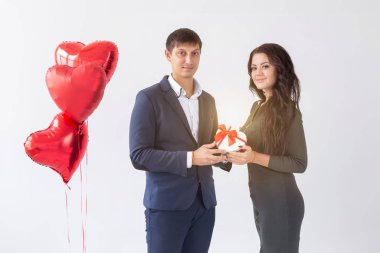 Sevgililer günü, tatil ve hediye konsepti. Sevgililer Günü hediyesi olan mutlu genç çift beyaz bir arka planda izole edilmiş. Mutlu Adam kız arkadaşına hediye veriyor..