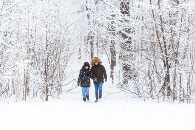 Karlı bir parkta yürüyen genç bir çift. Kış mevsimi.
