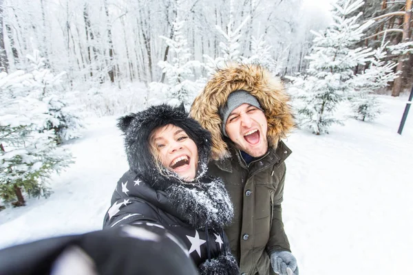 Sezon, miłość, technologia i wypoczynek koncepcja - szczęśliwa para robi selfie przez smartfona na tle zimy — Zdjęcie stockowe