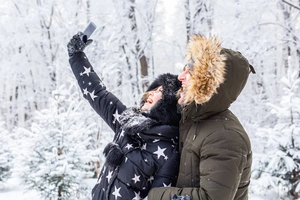 Sezon i koncepcja związku - śmieszne para biorąc selfie w okresie zimowym — Zdjęcie stockowe