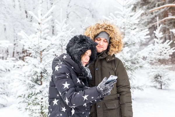 Tecnologias e conceito de relacionamento - Feliz casal sorrindo tirar uma selfie em uma floresta de inverno fora — Fotografia de Stock