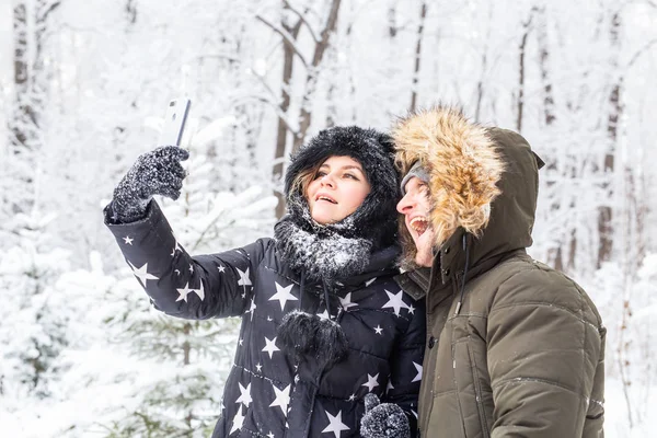 Homme prenant selfie photo jeune couple romantique sourire neige forêt plein air hiver — Photo