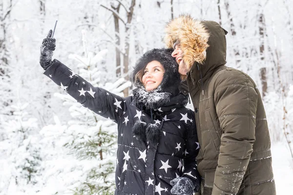 Conceito de temporada e relacionamento - Casal engraçado tomando selfie no tempo de inverno — Fotografia de Stock