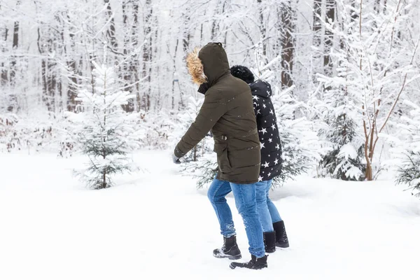 Un jeune et beau couple s'amuse dans le parc enneigé, courant et se tenant la main. Concept de Saint-Valentin. Saison d'hiver. — Photo