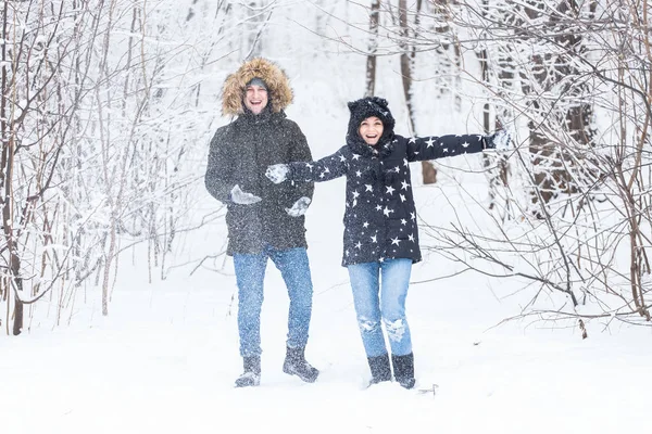 Amor, relacionamento, estação e conceito de amizade - homem e mulher se divertindo e brincando com a neve na floresta de inverno — Fotografia de Stock