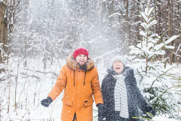 Amour, saison, amitié et concept de personnes - jeune homme et femme heureux s'amuser et jouer avec la neige dans la forêt d'hiver — Photo