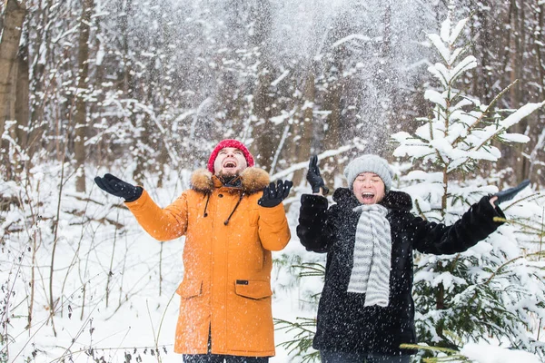 愛、季節、友情と人々の概念-幸せな若い男性と女性は冬の森の中で雪と遊んでいます — ストック写真
