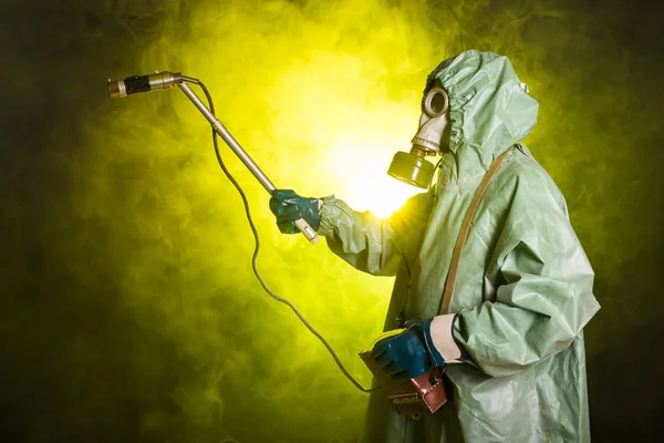 Radiation, pollution and danger concept - Man in protective clothing and a gas mask on a dark background