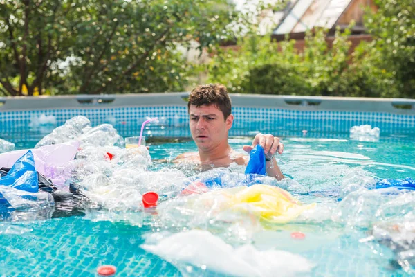 Ecology, plastic trash, environmental emergency and water pollution - shocked man swim in a dirty swimming pool