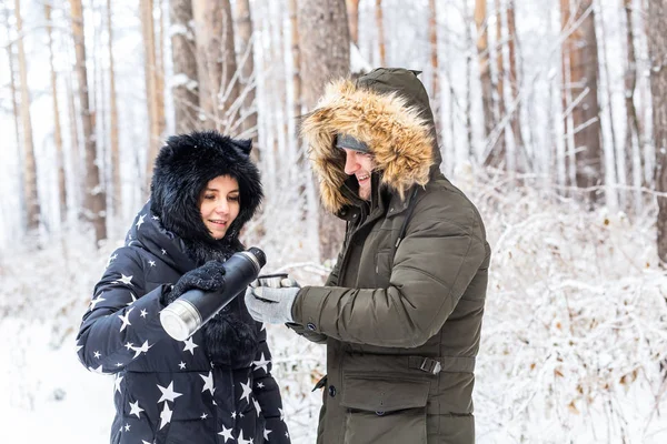 Concept de saison et de marche - Happy couple buvant du thé chaud dans la forêt d'hiver — Photo