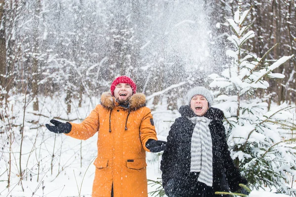 Amour, saison, amitié et concept de personnes - jeune homme et femme heureux s'amuser et jouer avec la neige dans la forêt d'hiver — Photo