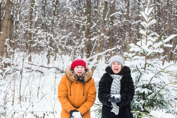 Miłość, sezon, przyjaźń i koncepcja ludzi - szczęśliwy młody mężczyzna i kobieta bawią się i bawią się śniegiem w zimowym lesie — Zdjęcie stockowe