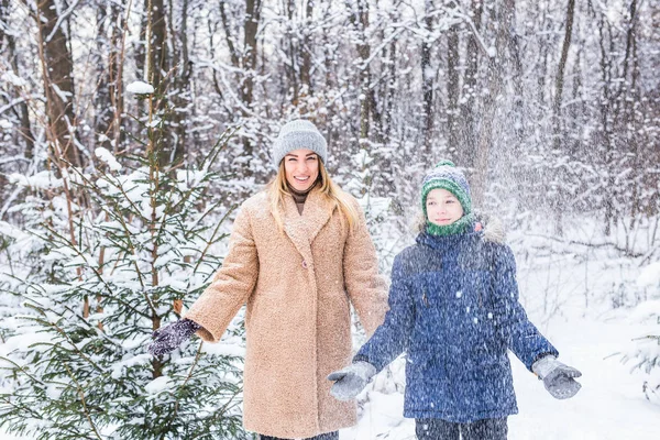 Parenting, fun et concept de saison - Bonne mère et son fils s'amusent et jouent avec la neige dans la forêt d'hiver — Photo