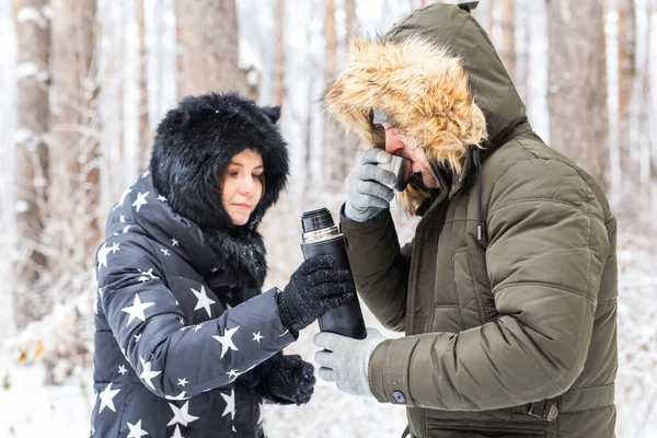 Concept de saison et de marche - Happy couple buvant du thé chaud dans la forêt d'hiver — Photo