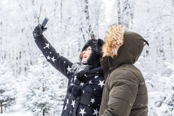 Homme prenant selfie photo jeune couple romantique sourire neige forêt plein air hiver — Photo