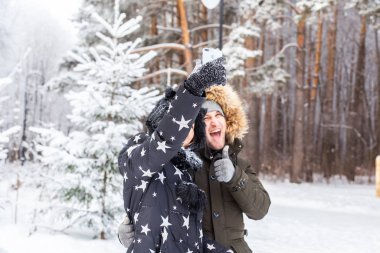 Sezon, aşk, teknoloji ve eğlence konsepti. Mutlu çift kış arkaplanı boyunca akıllı telefonla selfie çekiyor.