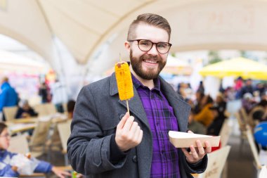 Vejetaryen ve yemek konsepti - Yakışıklı adam fast food festivalinde mısır yiyor