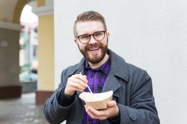 Man holding one-off plate with traditional delicious jewish food falafel made of chickpeas at the street food festival. Very tasty fried vegetarian meal.
