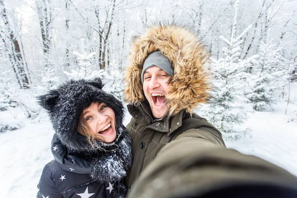 Conceito de temporada e relacionamento - Casal engraçado tomando selfie no tempo de inverno — Fotografia de Stock