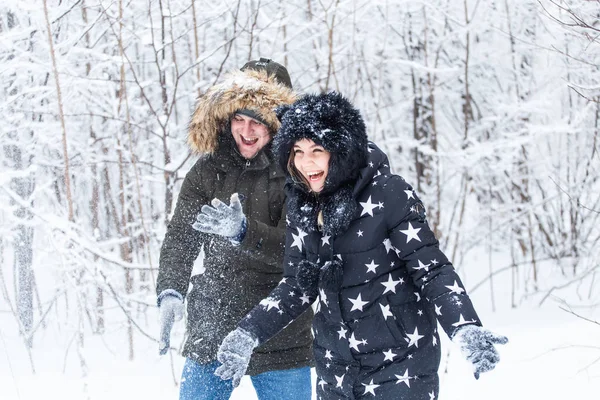 L'amour, la relation, la saison et le concept d'amitié - l'homme et la femme s'amusent et jouent avec la neige dans la forêt hivernale — Photo