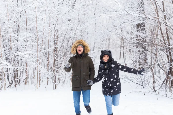 Casal feliz caminhando por uma floresta nevada no inverno — Fotografia de Stock