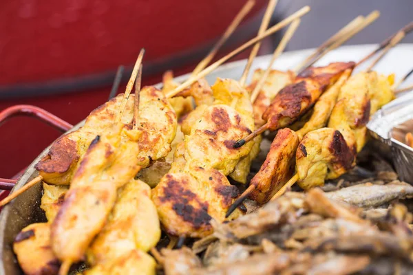 Street Food and meal concept. Grilled chickens inserted on wooden skewers was putting on street shop shelf with many other stuffs