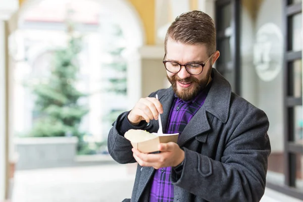 Концепция быстрого питания и еды - Молодой человек ест еду на улице — стоковое фото