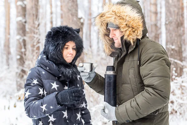 Młoda para zakochana pije gorący napój z termosu i cieszy się zimową przyrodą. — Zdjęcie stockowe