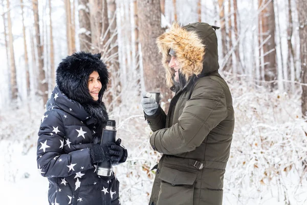 Conceito de temporada e caminhada - casal feliz bebendo chá quente na floresta de inverno — Fotografia de Stock