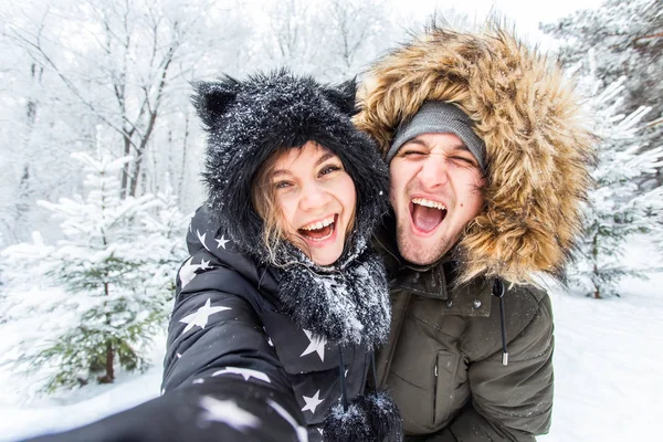 Genç romantik çiftin fotoğrafını çeken adam açık havada kar ormanlarında gülümsüyor. — Stok fotoğraf