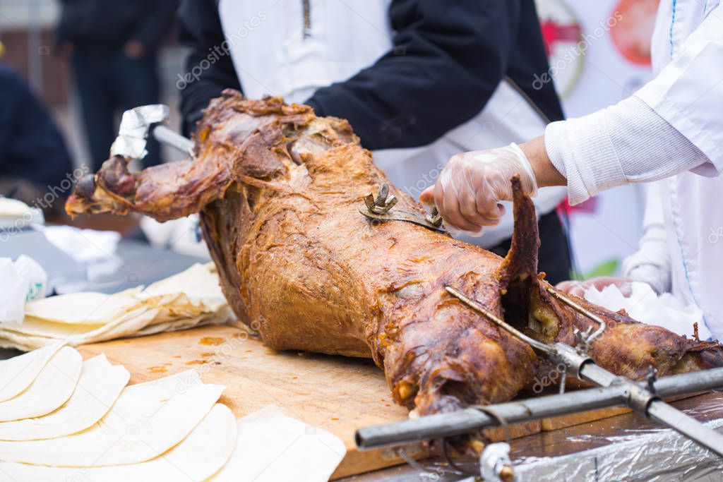 The carcass of a lamb is roasted on a spit. Close-up carcass of a sheep that is roasting on the spit.