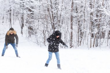 Yaşam tarzı, sezon ve eğlence konsepti - kış parkında kartopu oynayan komik çift