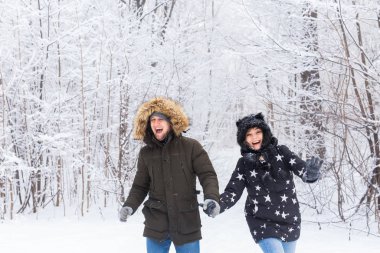 Mutlu çift kışın karlı bir ormanda yürüyor.