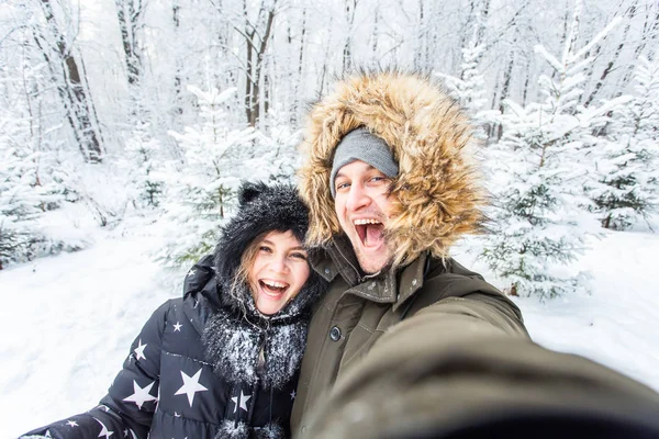 Mężczyzna biorąc selfie zdjęcia młody romantyczny para uśmiech śnieg las zewnątrz zima — Zdjęcie stockowe