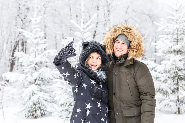 Homme prenant selfie photo jeune couple romantique sourire neige forêt plein air hiver — Photo