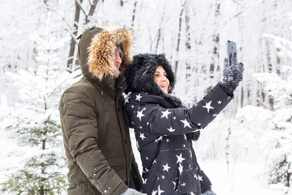 Concept de saison et de relation - Couple drôle prenant selfie en hiver — Photo