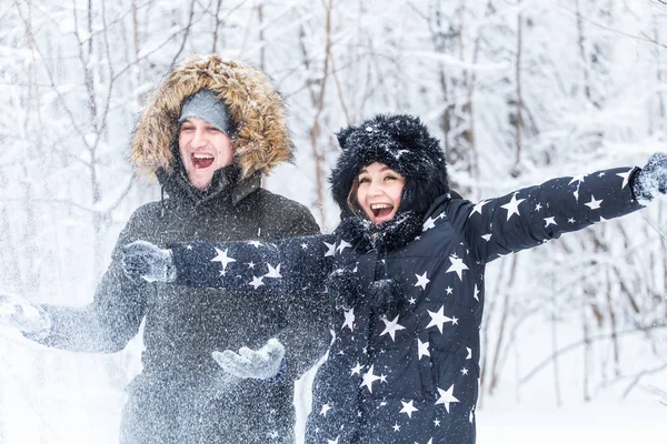 L'amour, la relation, la saison et le concept d'amitié - l'homme et la femme s'amusent et jouent avec la neige dans la forêt hivernale — Photo