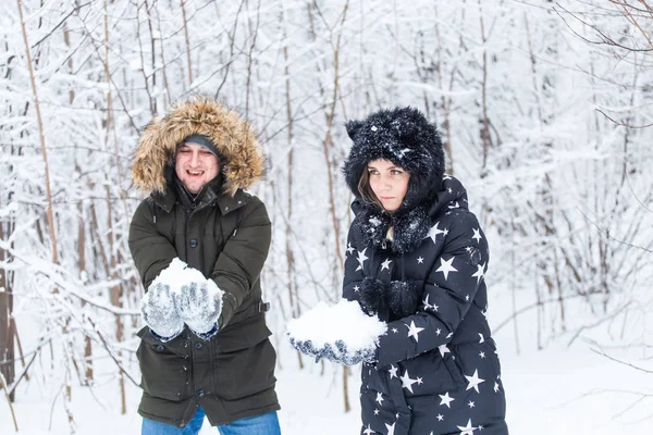 Amor, relación, temporada y concepto de amistad - hombre y mujer divirtiéndose y jugando con la nieve en el bosque de invierno — Foto de Stock