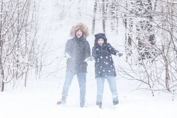 Молода пара грає зі снігом в зимовому парку — стокове фото