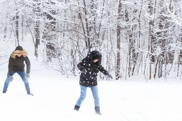 Mode de vie, saison et concept de loisirs - Couple drôle jouant boule de neige dans le parc d'hiver — Photo